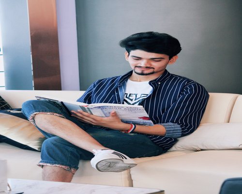 A relaxed man sitting on a comfortable sofa reading a book
